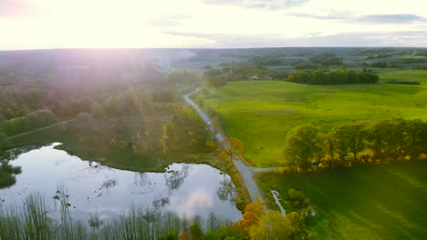 Aerial-footage-at-the-pond-in-autumn,-trees-without-leaves,-bald-stems-of-trees,-colorful-landscape-around,-beautiful-sunset,-warmiaand-masuria,-Poland