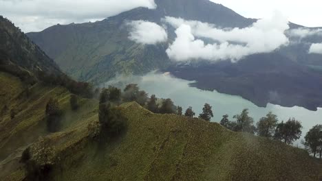 Toma-Panorámica-Aérea-4k-Del-Monte-Rinjani-Con-Niebla-Con-El-Lago-Del-Cráter-En-La-Vista-2,-Indonesia