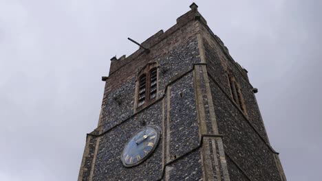 Low-angle-shot-of-old-church-tower-with-clock-on-overcast-afternoon