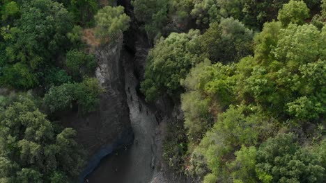 4K-AERIAL:-Drone-descending-above-Alcantara-Gorges,-an-impressive-channel-of-lava-columns-eroded-naturally-into-ravines,-canyons-and-caves
