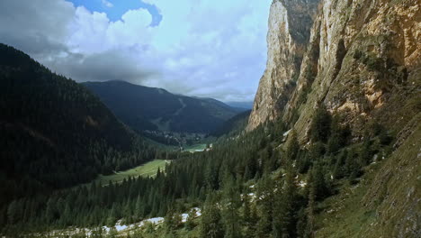 Grüner-Talboden,-Dunkelgrüne-Fichten,-Ein-Hauch-Von-Blauem-Himmel-Und-Imposante-Felswände