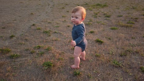 Happy-sitting-toddler-quickly-stands-up-at-beach-and-takes-first-steps-forward