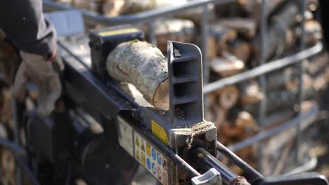 Log-cutting-machine-chopping-wood,-static-handheld-slow-motion,-shallow-depth-of-field
