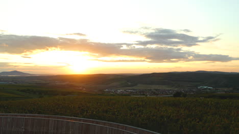 Peak-and-view-from-the-Kobylí-lookout-point-Peak-during-sunset-overlooking-the-wooden-construction-in-the-background-of-the-sun-and-a-farm-with-grape-vines-moving-clouds-area-of-South-Moravia