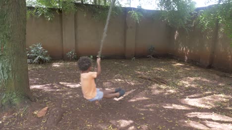 A-young-mixed-raced-boy-swinging-on-a-rope-swing-in-backyard