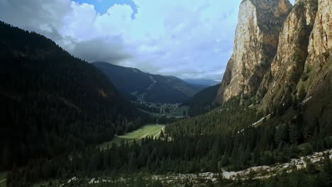 Sideways-flight-right-to-left-across-a-beautiful-alpine-mountain-valley-with-sheer-rock-on-the-right-and-wooded-hills-on-the-left