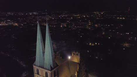Vista-Nocturna-Aérea-De-Una-Iglesia-En-El-Casco-Antiguo-De-Olsztyn,-Polonia