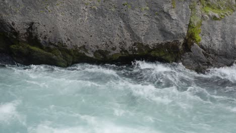 A-close-up-shot-of-rough-water-flowing-past-a-rock-in-the-Huka-Falls-in-Taupo,-NZ