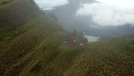 AERIAL-4K-Panning-Up-Shot-of-Campsite-on-Crater-Rim-with-Lake-in-Background,-Mount-Rinjani-Indonesia