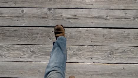 Walking-on-a-boardwalk-looking-down-at-leg-and-feet-with-boots-on