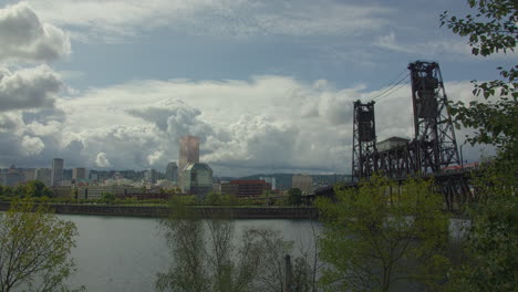Lift-bridge,-towering-cumulus-clouds,-riverfront-cityscape,-time-lapse