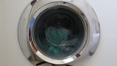 Washing-machine-is-running-the-program-to-wash-the-bed-sheets-in-the-afternoon,-view-from-the-porthole