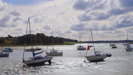 Handheld-shot-of-a-pair-of-boats-with-many-more-in-the-background-at-low-tide-in-a-river-in-the-mud