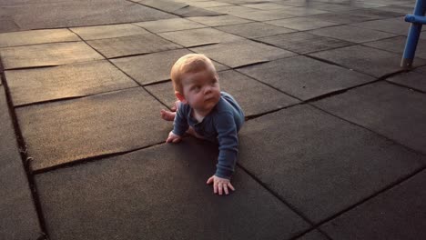 Happy-toddler-boy-lays-down-on-rubber-playground-mat-as-sun-sets-on-warm-summer-evening