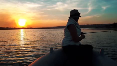 Footage-of-a-girl-fishing-in-a-lake-on-a-boat-with-a-beautiful-sunset-in-South-Africa