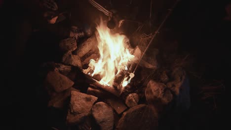 campfire---bonfire-with-stones-around-in-the-dark-with-hands-holding-marshmallow-inside-the-fire