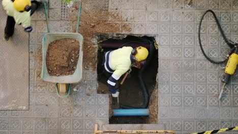 Top-View-Close-Up-Of-Constructor-Worker-Digging-Shoveling-and-Breaking-a-Concrete-on-a-street-in-Barcelona
