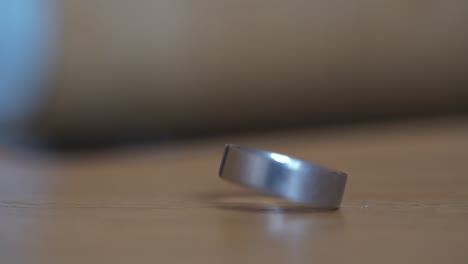 Close-up-shot-of-wedding-ring-spinning-in-Slow-Motion-on-wooden-surface,-shallow-depth-of-field