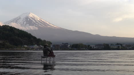 Wide-handheld-shot-of-a-fishermann-sitting-in-the-water-of-Lake-Kawaguchiko-with-Mt