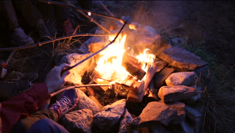 campfire---bonfire-with-stones-around-in-the-dark-with-hands-holding-marshmallow-inside-the-fire