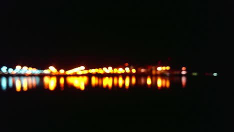 Verschwommene-Hafenlichter-Mit-Wunderschönen-Farben-Und-Fackeln,-Wenn-Die-Kamera-Nach-Rechts-Schwenkt