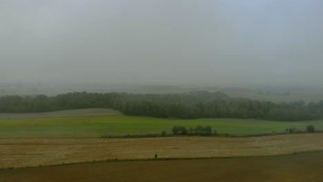 Aerial-footage-over-filed-during-foggy-morning,-Cloudy-sky-and-natural-landscape-around,-drone-4K,-warmia-and-masuria,-Poland