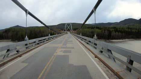 POV-through-the-rear-window-while-driving-the-Alaska-Highway-over-the-suspension-bridge-over-the-Liard-River-in-Liard-Hot-Springs-Provincial-Park-in-the-northern-Canadian-Rockies-in-British-Columbia