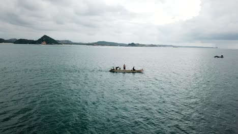 AERIAL-4K-Men-Standing-on-Fishing-Boat-in-Bay,-Indonesia