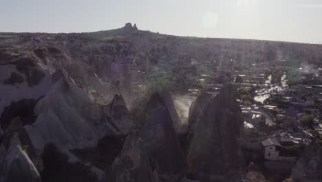 Aerial-flyover-of-chimney-rock-formations,-light-flares-and-dust-storm-in-Goreme,-Turkey