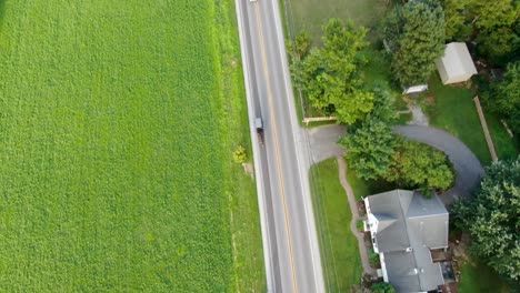 Amish-buggy-on-busy-country-road,-cars-pass-by,-descending-aerial-drone-shot