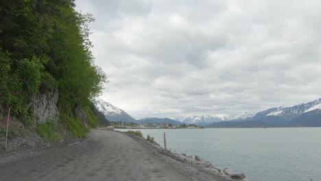 POV---Driving-on-Lowell-Point-Road-that-is-a-gravel-road-that-runs-along-a-tree-covered-mountain-side-and-drops-off-to-the-ocean-bay