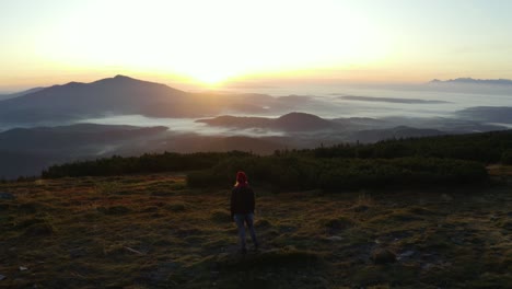 A-hiker-standing-on-a-rock-on-top-of-a-mountain-during-sunrise
