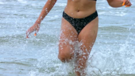 Close-up-of-legs-and-belly-of-a-woman-in-a-bikini-running-out-of-the-water