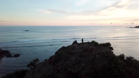 AERIAL-4K-Silhouettes-Standing-on-Edge-of-Cliff-Near-Ocean-at-Sunset