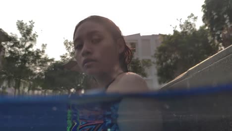 Geteilte-Unterwasseraufnahme-Eines-Südostasiatischen-Mädchens,-Das-In-Die-Kamera-Schaut