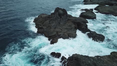 AERIAL-4K-Flyover-Large-Rocks-on-Edge-of-Ocean-with-Waves-Crashing,-Indonesia
