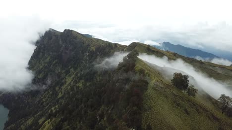 AERIAL-4K-Clouds-Pouring-over-Mount-Rinjani-Crater-Rim,-Indonesia