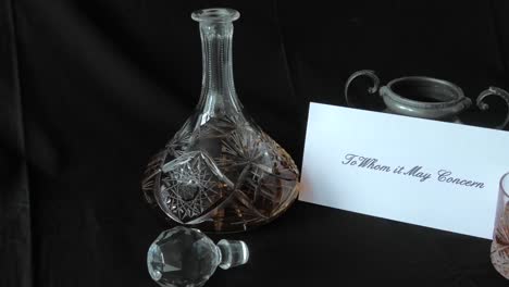 An-envelope-addressed-to-Whom-it-May-Concern-is-put-on-a-desk-beside-a-whisky-decanter