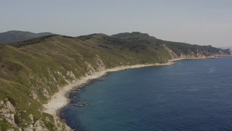 Fly-over-steep-cliff-coastline-with-deep-blue-ocean-on-a-clear-sunny-day