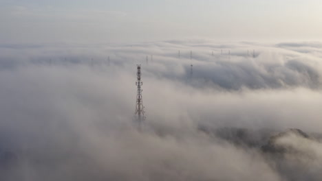 Fernmeldeturm-In-Einem-Dichten-Nebel,-Der-Sich-Am-Nachmittag-über-Hügel-Bewegt