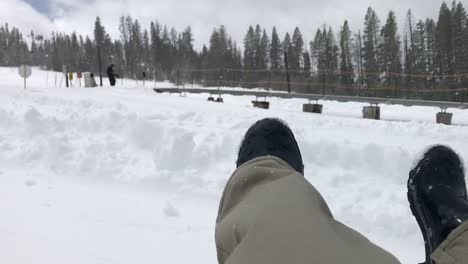 POV-Aufnahmen-Von-Snowtubing,-Das-Einen-Schneebedeckten-Berg-Hinunterfährt,-Während-Weiße-Schneeflocken-Vom-Himmel-Fallen