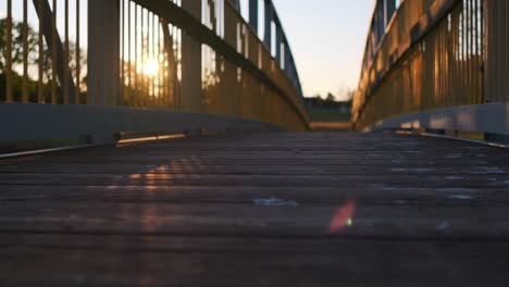 Sun-shining-through-the-metal-rails-of-a-wooden-pedestrian-bridge-during-sunset