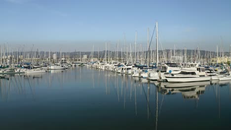 A-slow-pan-left-over-mirror-like-water-with-sailboats-parked-in-their-ports