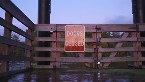 Ground-shot-of-Docks-Closed-sign-at-a-closed-boating-docks-gate-during-sunset