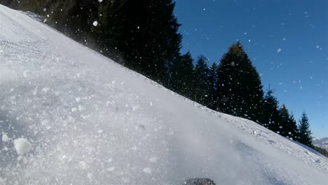 Zeitlupe,-Ein-Skifahrer,-Der-Einen-Steilen-Hang-Hinunterfährt,-Im-Hintergrund-Ein-Blauer-Himmel-Mit-Strahlender-Sonne-Und-Schnee,-Der-Von-Den-Skiern-Aufsteigt.-Blick-Vom-Rücken-Des-Skifahrers