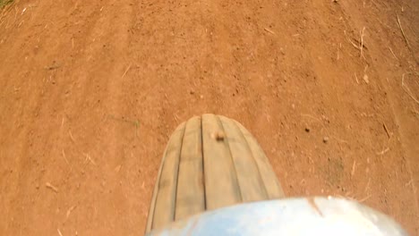 A-action-shot-of-a-motor-bike-wheel-turning-fast-while-speeding-along-a-dirt-rural-road