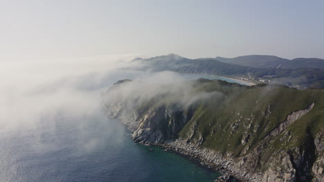 Bird-eye-view-of-a-breathtaking-epic-rocky-coast-line-with-heavy-dense-fog-approaching-from-the-sea,-Far-east,-Russia