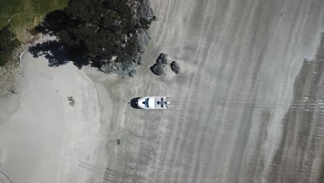 Aerial-bird-view,-of-an-amphibious-boat-on-a-sandy-beach-with-a-track-mark-created-from-travelling-from-the-sea