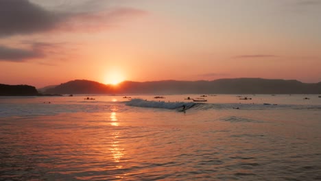 Amanecer-En-Los-Lugares-De-Surf-De-Gerupuk-En-Lombok,-Con-Vistas-A-La-Bahía-Con-Los-Barcos-De-Pesca-Y-Los-Surfistas