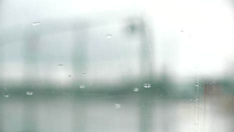 Abstract,-Focused-raindrops-wiped-away-from-windshield-with-defocused-car-lights-in-the-background